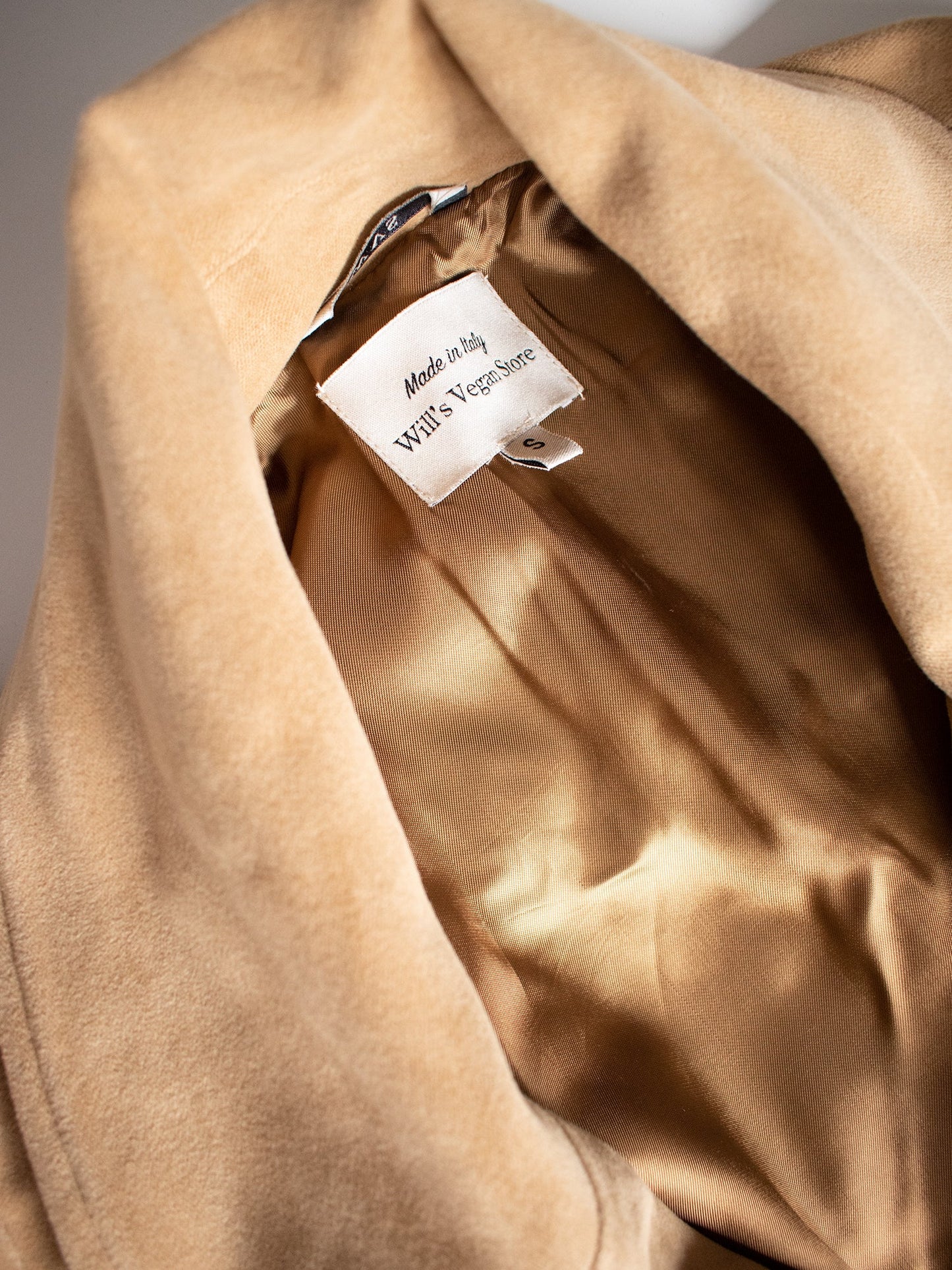 Close-up of a beige fabric with a label inside, on a neutral background