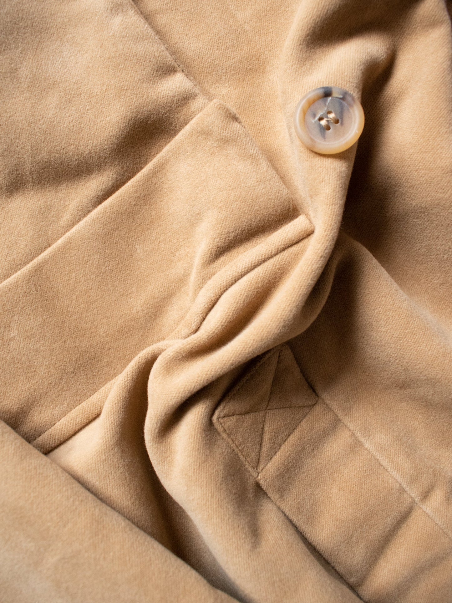 Close-up of beige fabric with a button and stitching detail