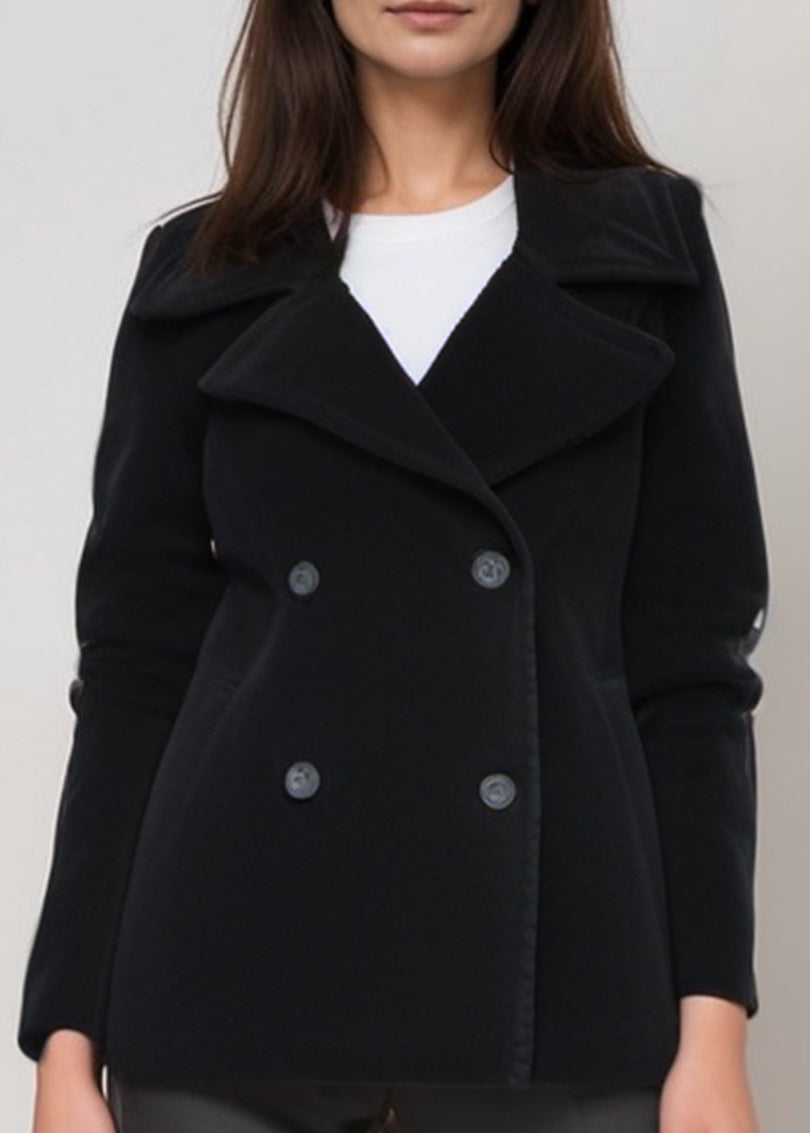 Person wearing a black coat and gray pants on a plain background