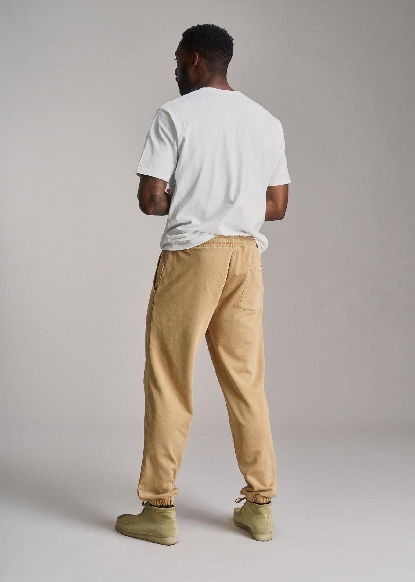 Person wearing a white t-shirt and beige pants against a plain background