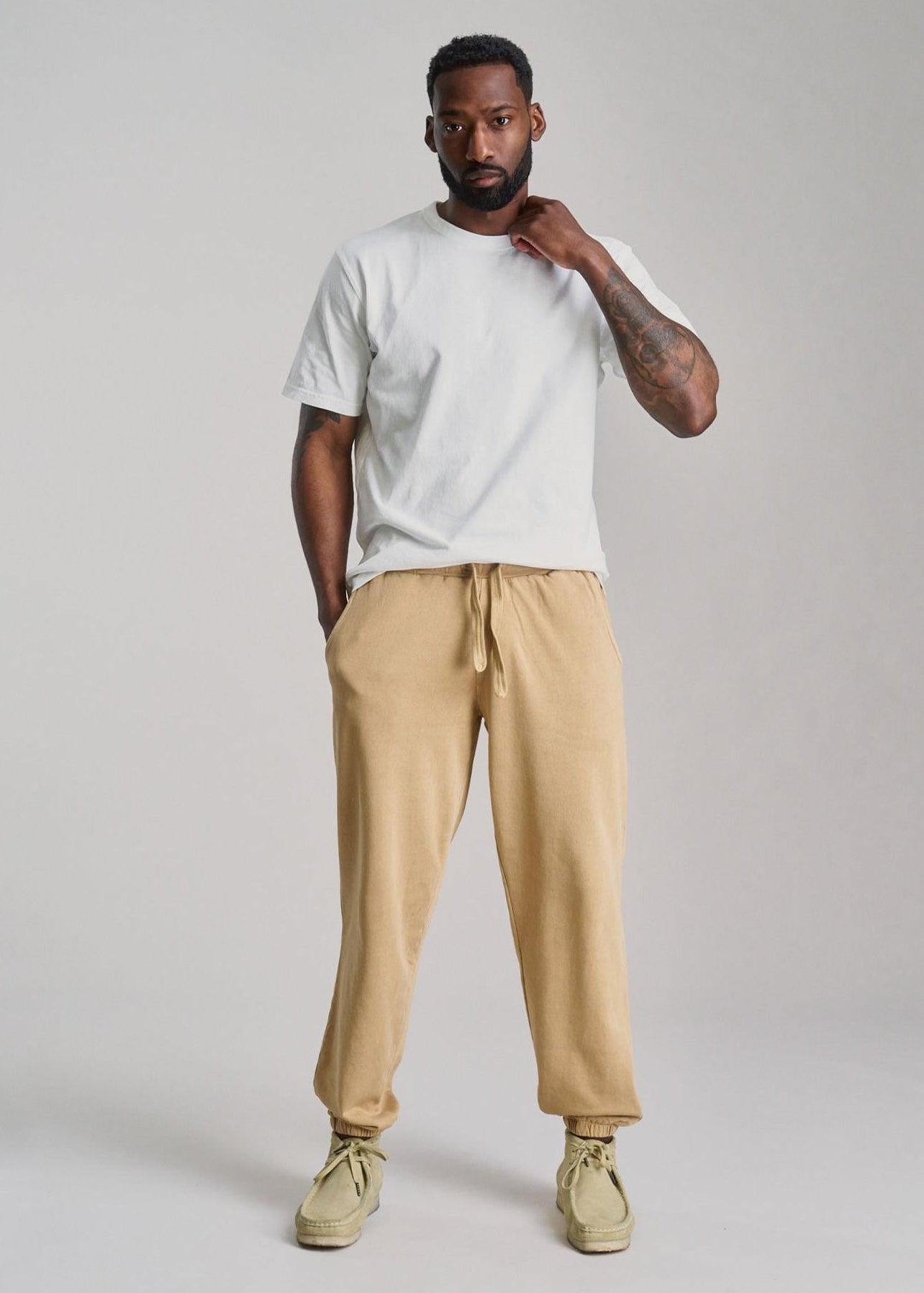 Man wearing a white t-shirt and beige pants on a plain background