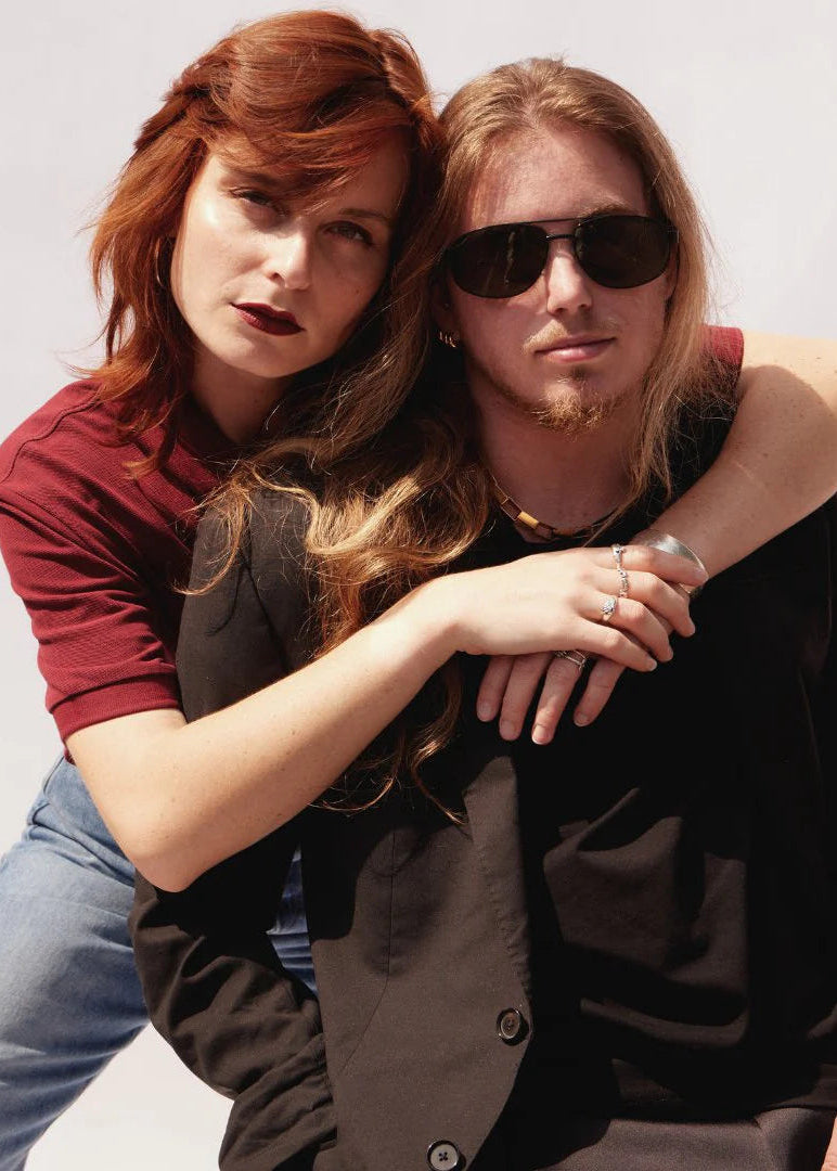 Two people posing closely against a plain background