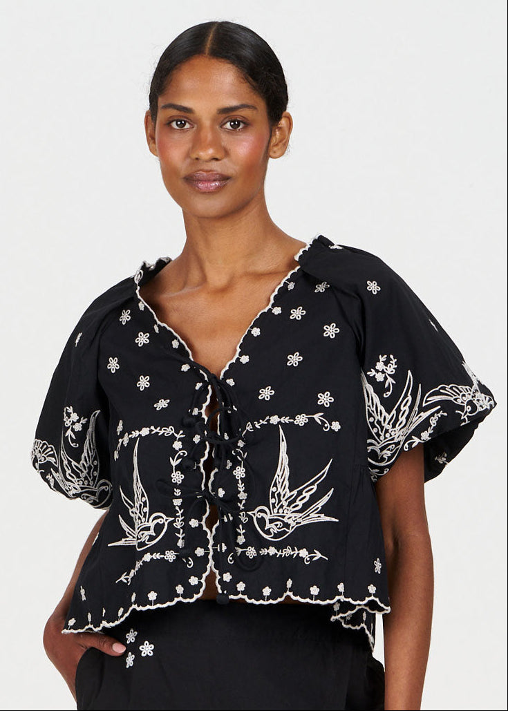 Model wearing the BEATRIX Organic Cotton Top - Black featuring intricate embroidery and a stylish design.