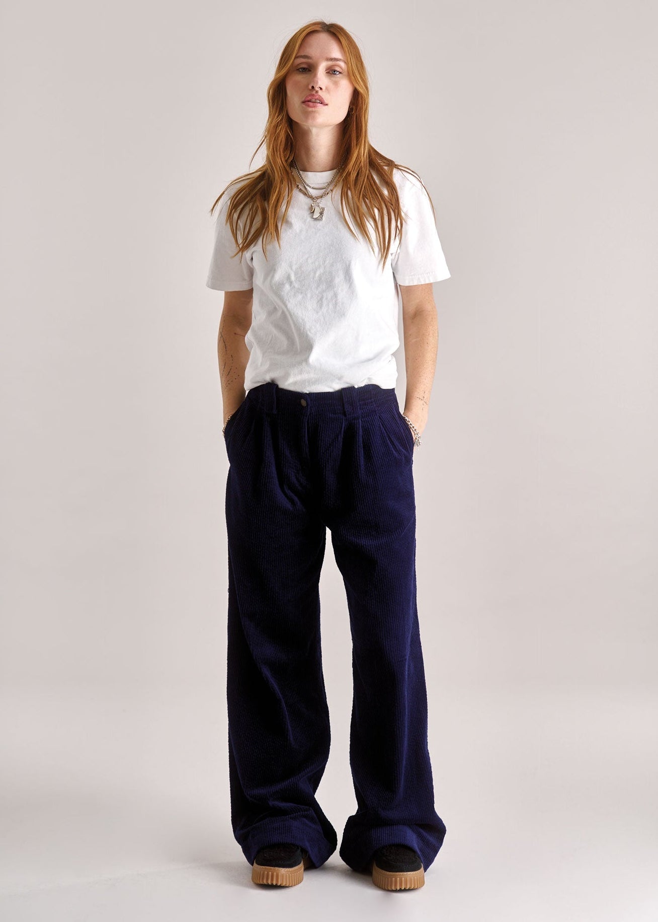 Person wearing a white t-shirt and navy pants on a plain background