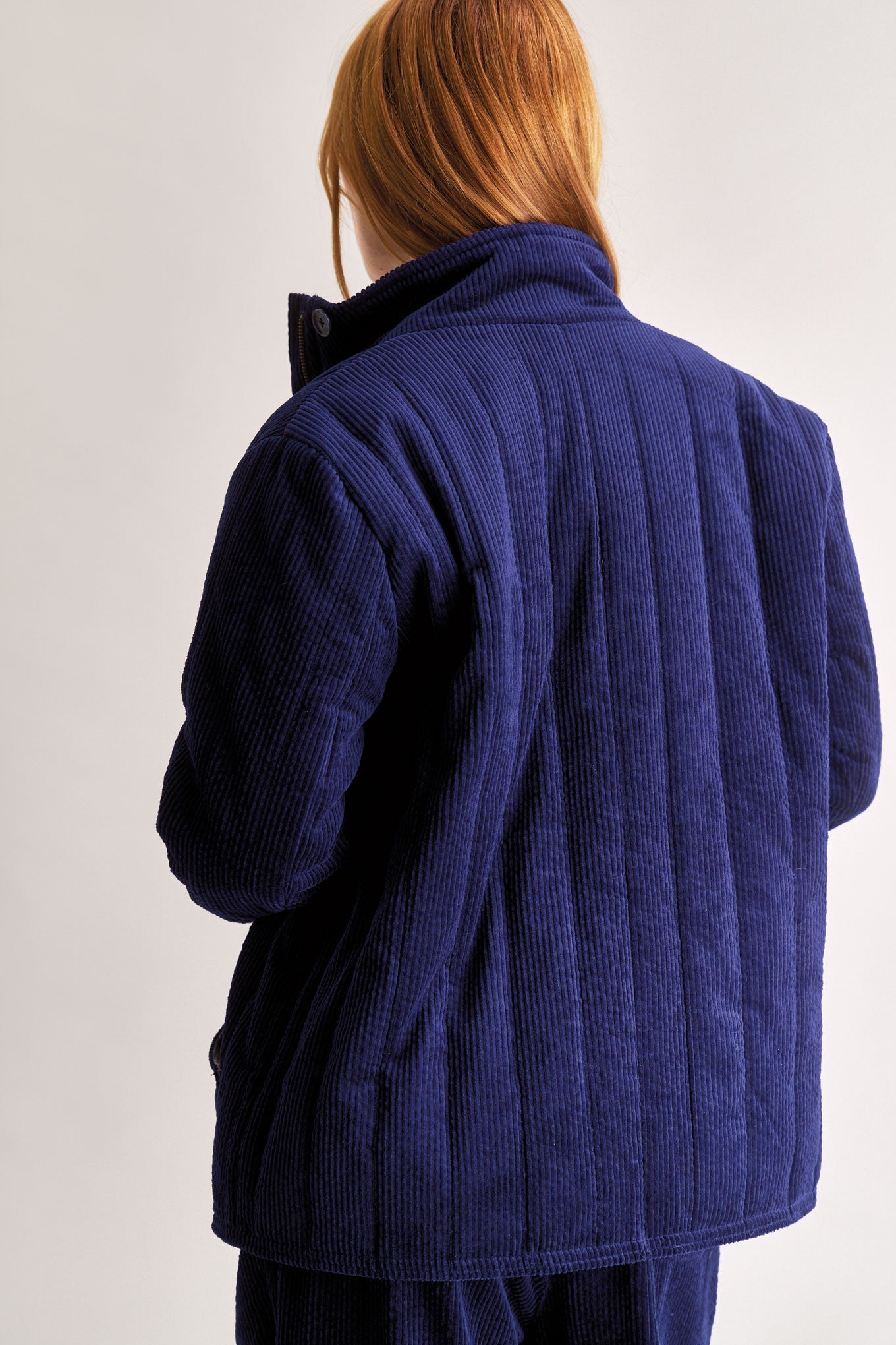 Person wearing a blue corduroy jacket against a plain background