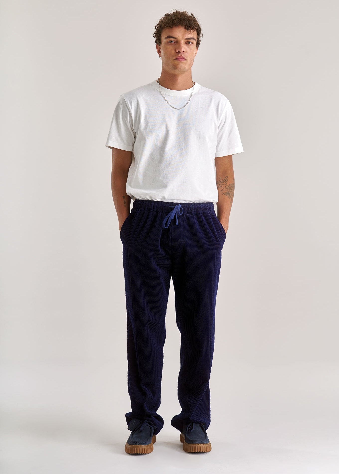 Person wearing a white t-shirt and navy pants on a plain background