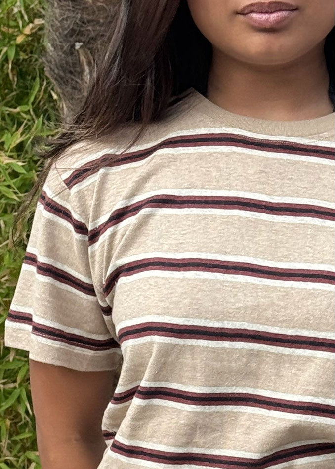 Person wearing a beige and brown striped shirt with a black skirt outdoors.