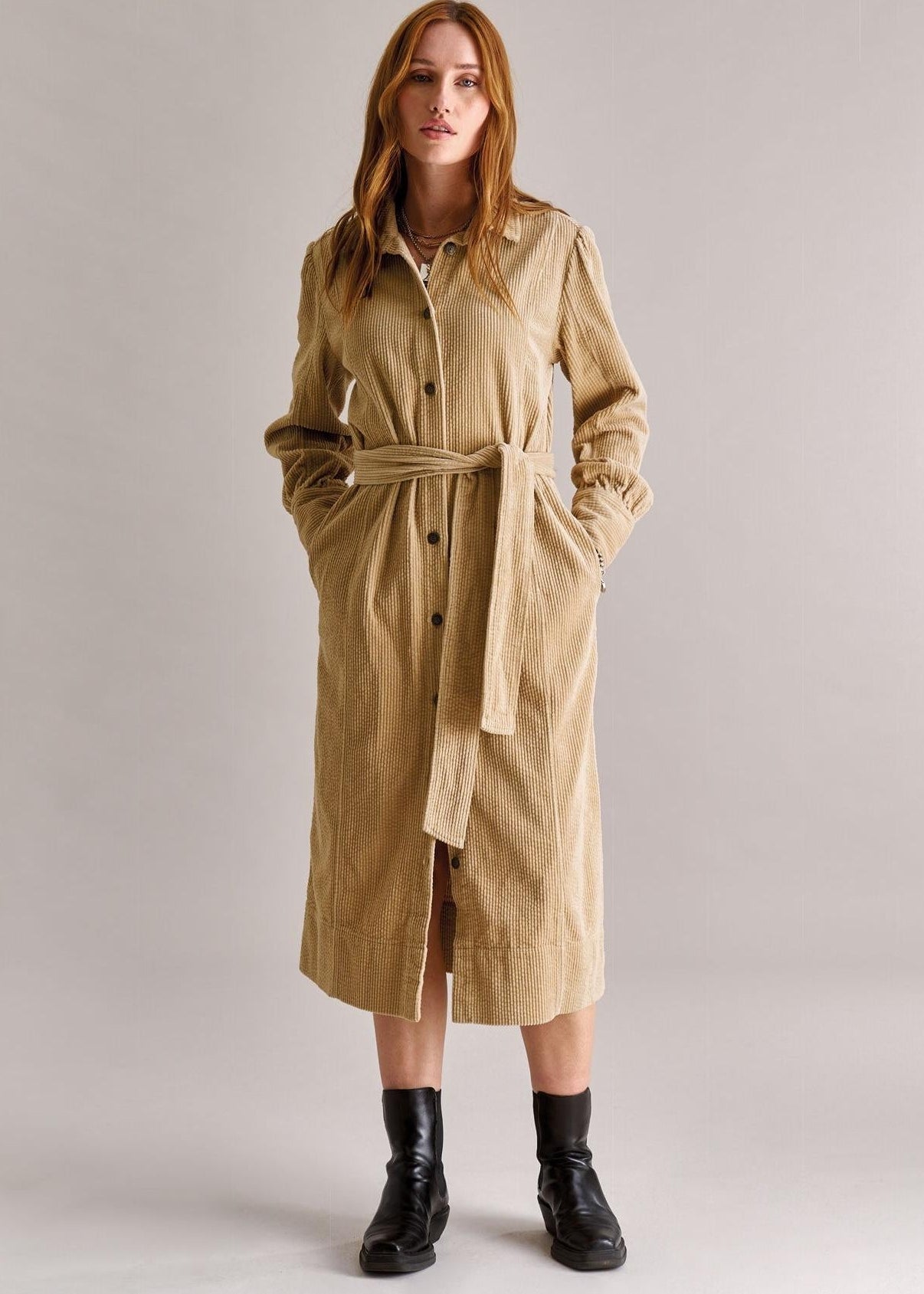 Woman wearing a beige trench coat on a plain background