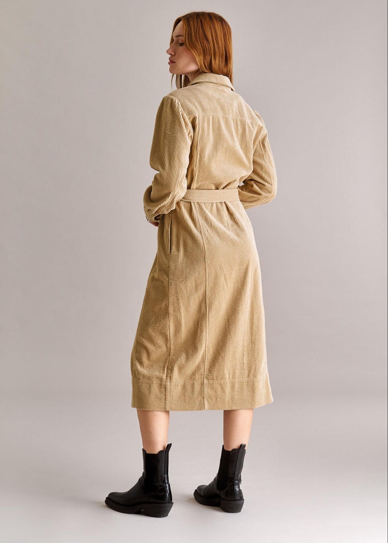 Woman wearing a beige trench coat on a plain background