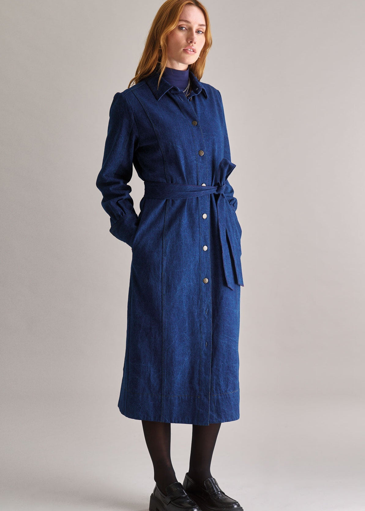 Woman wearing a blue trench coat on a plain background