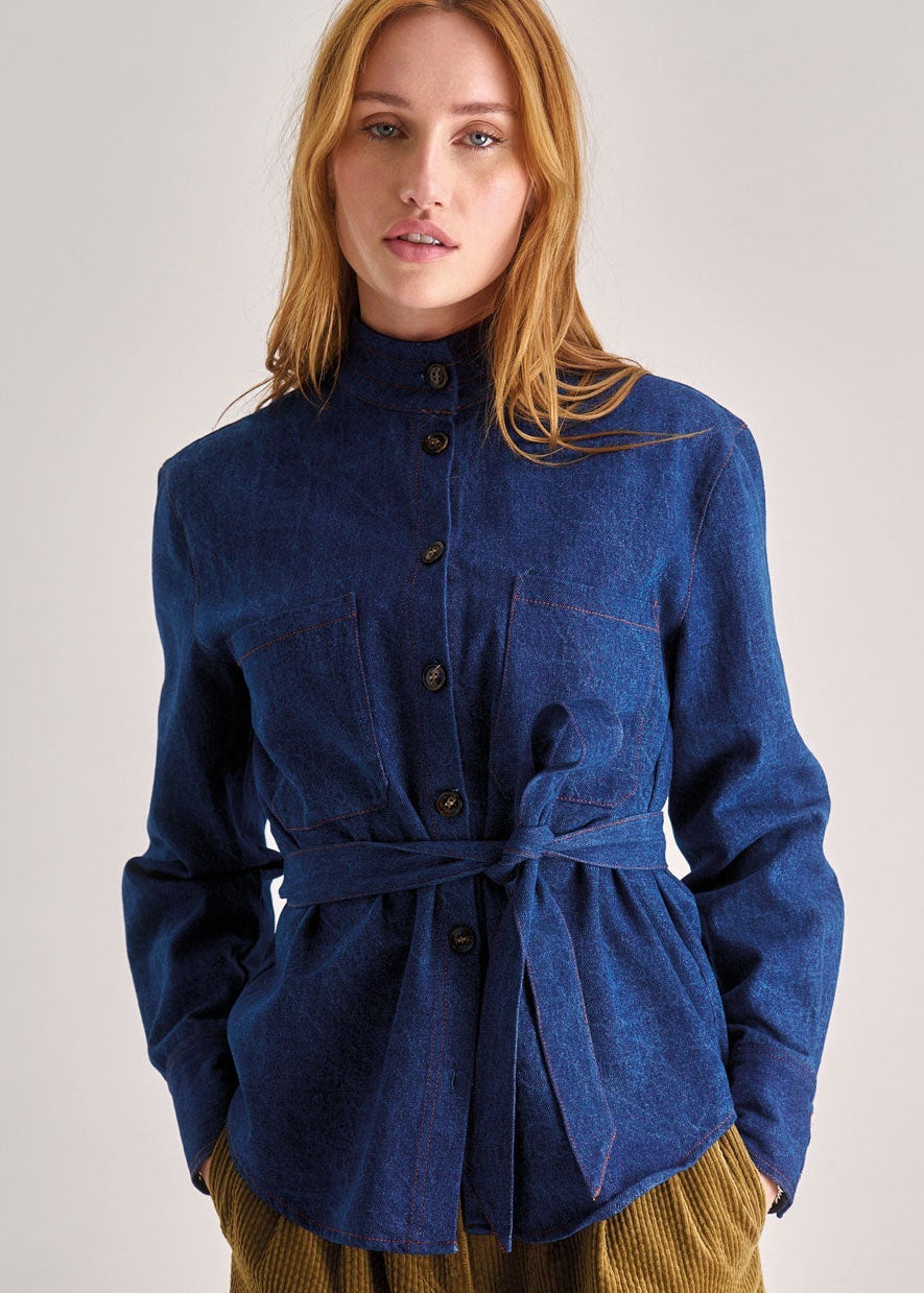 Woman wearing a blue jacket and brown pants on a white background