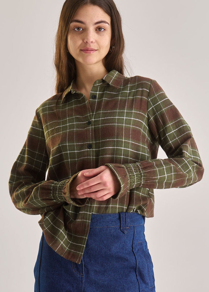 Person wearing a plaid shirt and blue pants on a plain background