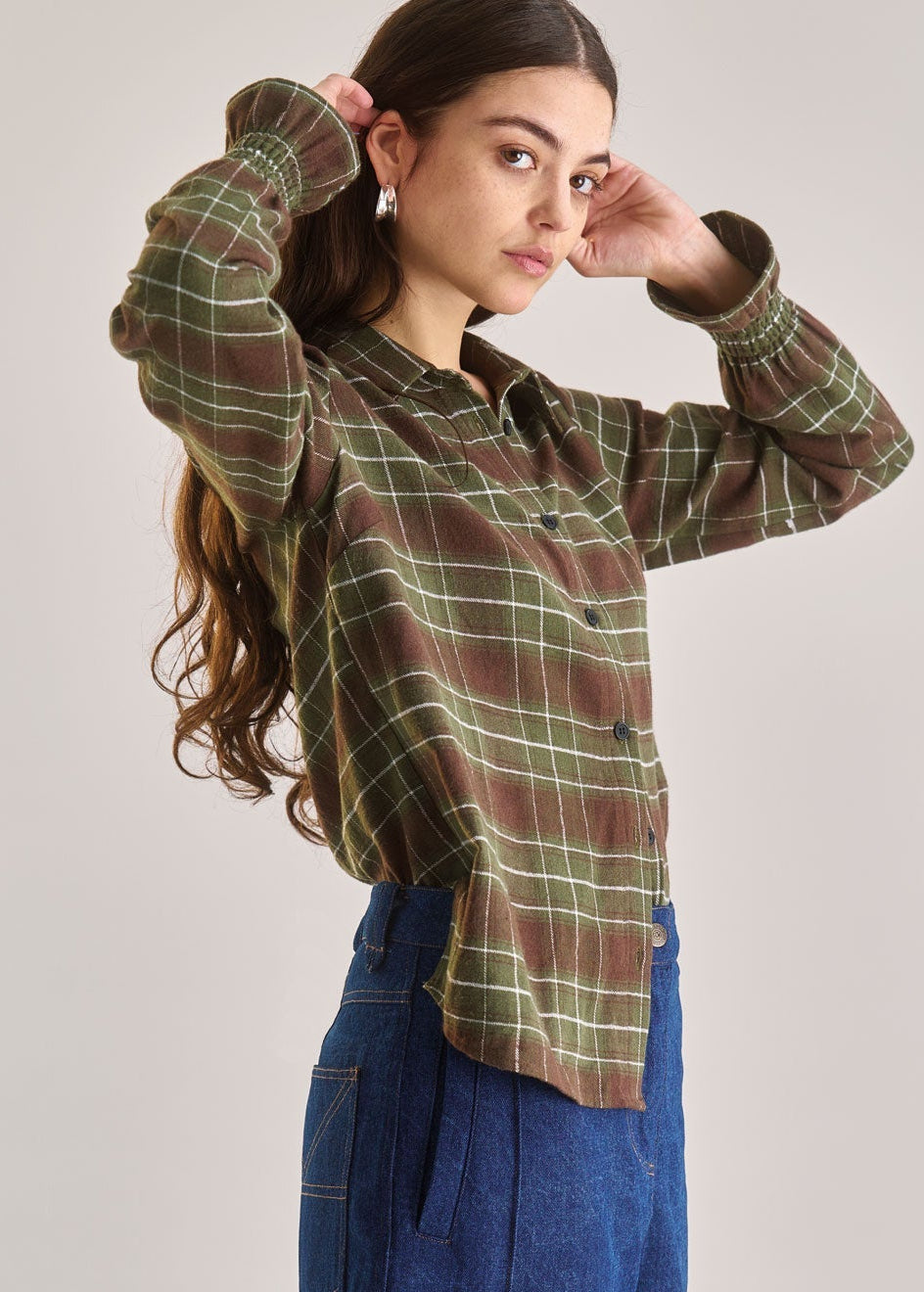 Person wearing a plaid shirt and blue pants against a plain background