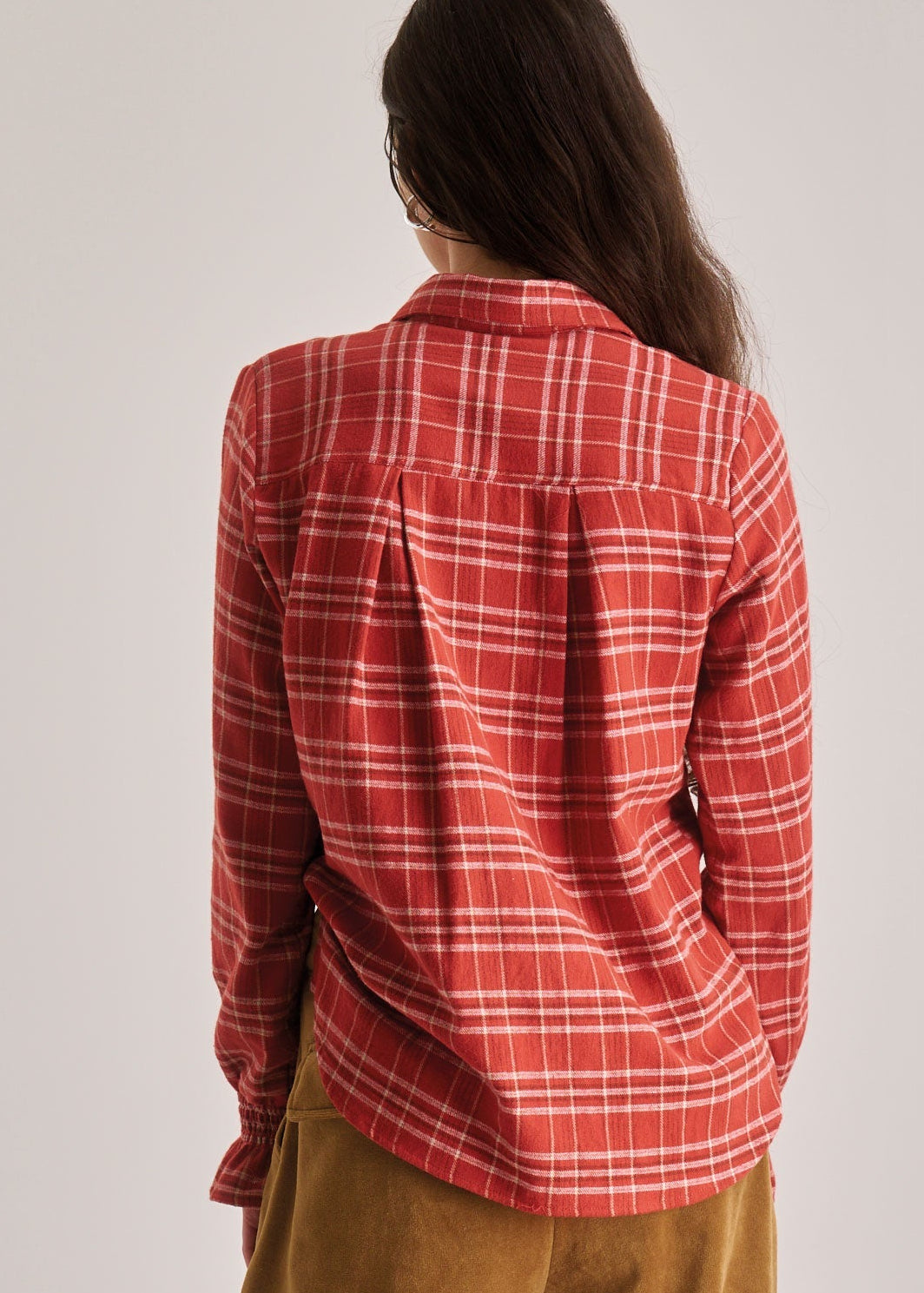Person wearing a red plaid shirt against a plain background