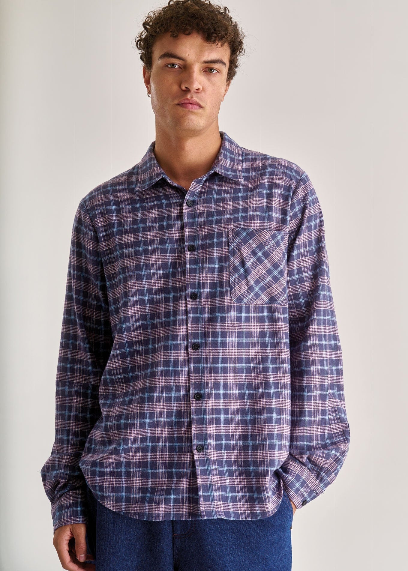 Man wearing a plaid shirt against a plain background