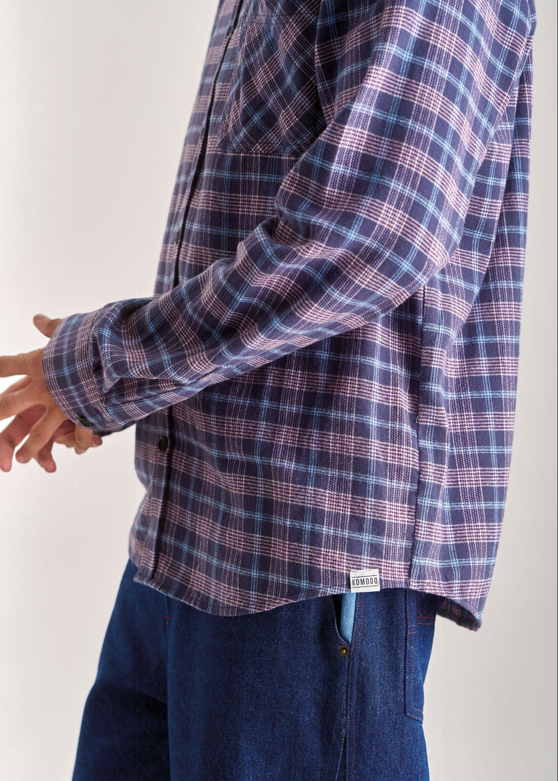 Person wearing a blue and purple plaid shirt with a white background