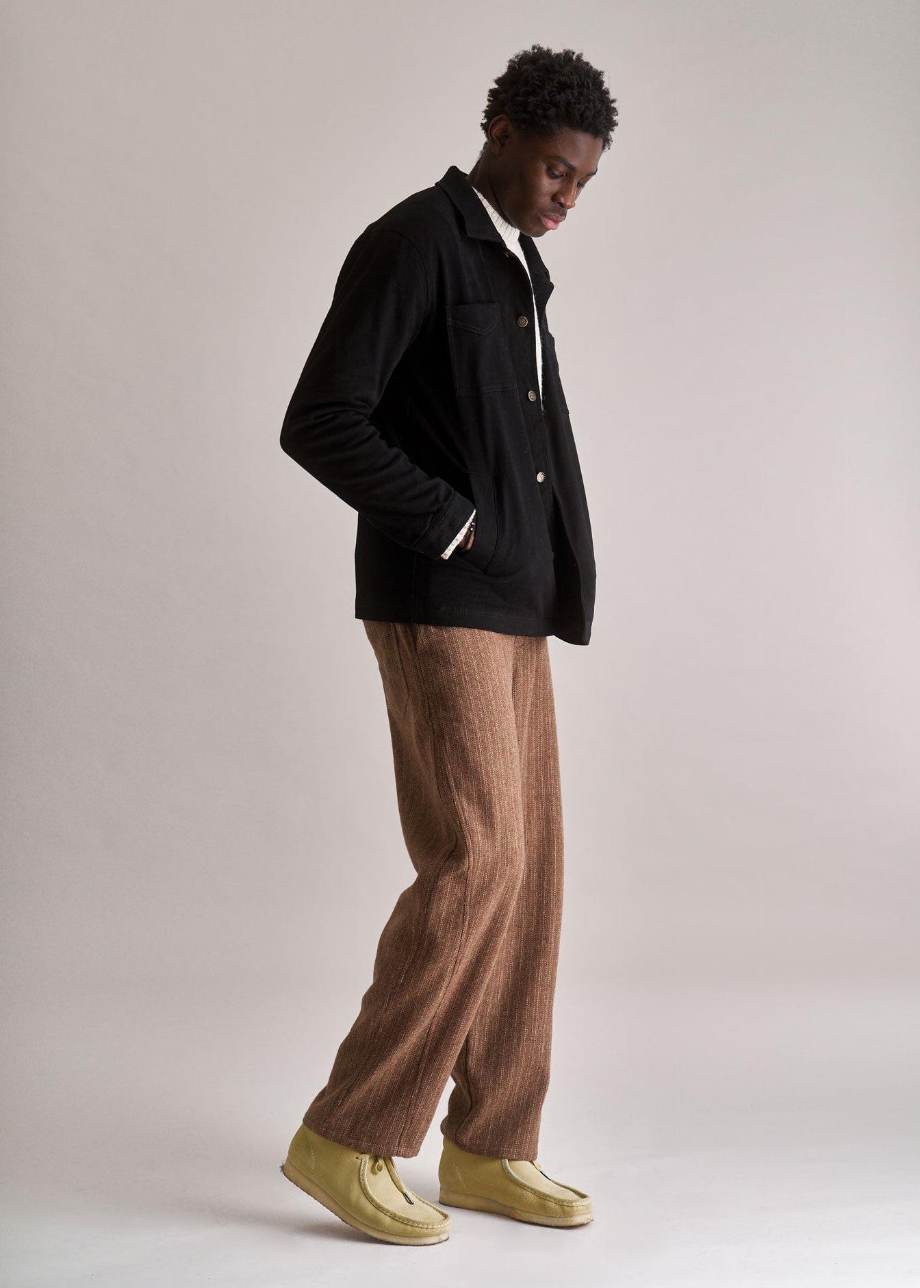 Person wearing a black jacket and brown pants on a plain background