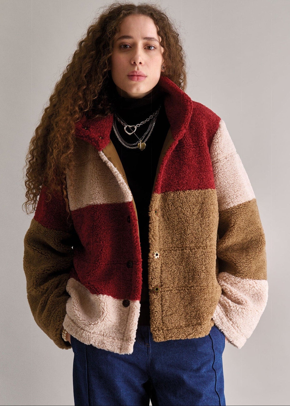 Person wearing a colorful patchwork jacket against a plain background