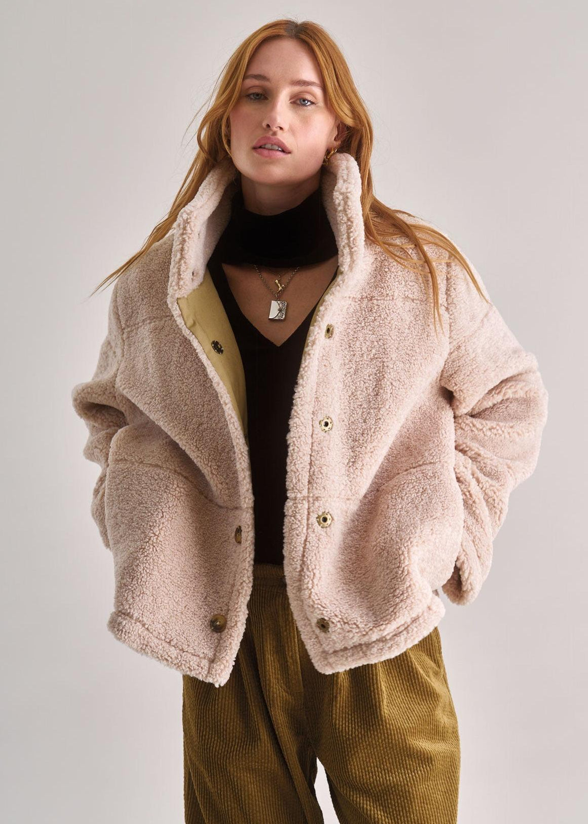Woman wearing a beige fleece jacket with a white background