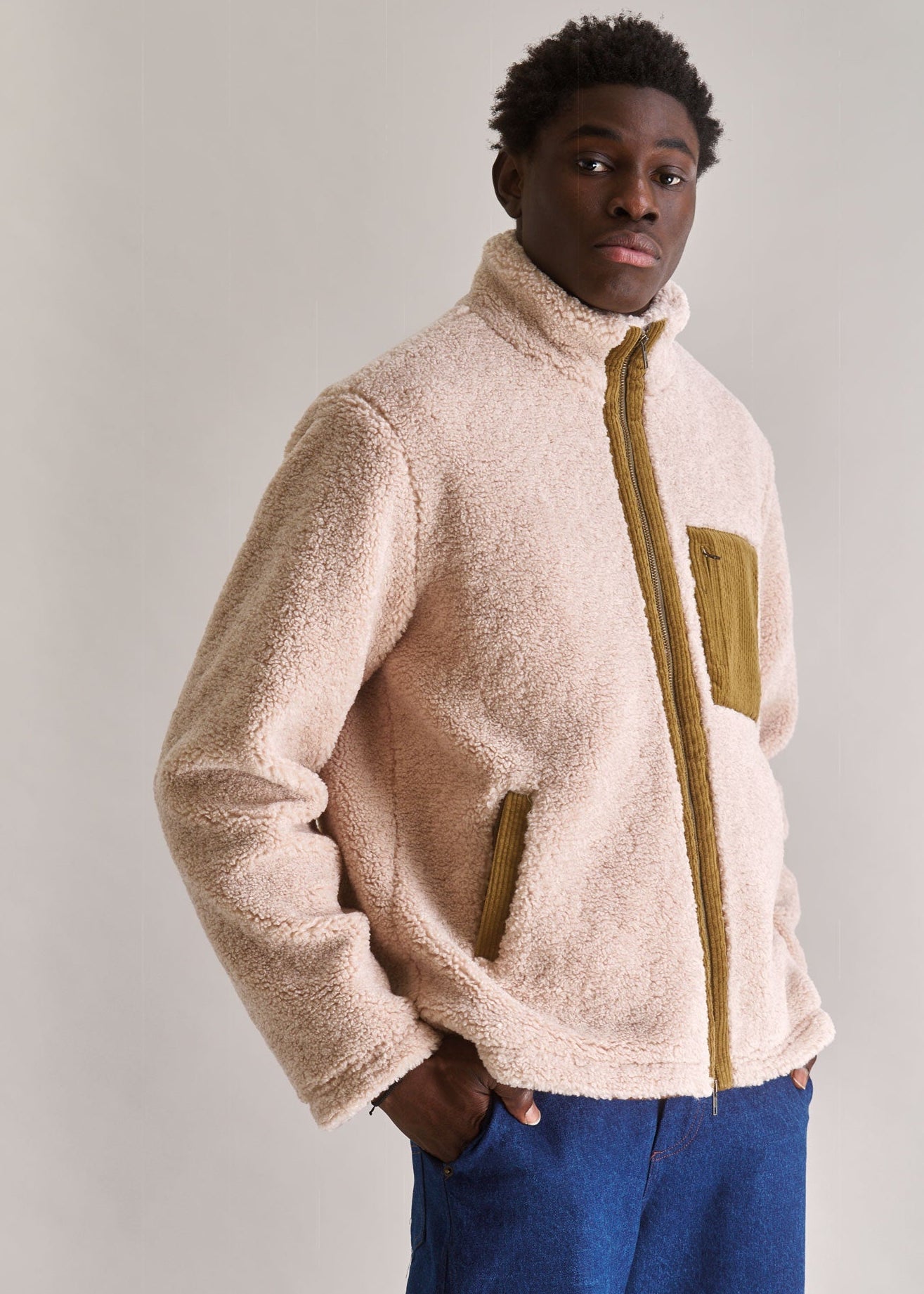 Person wearing a beige fleece jacket with a plain background