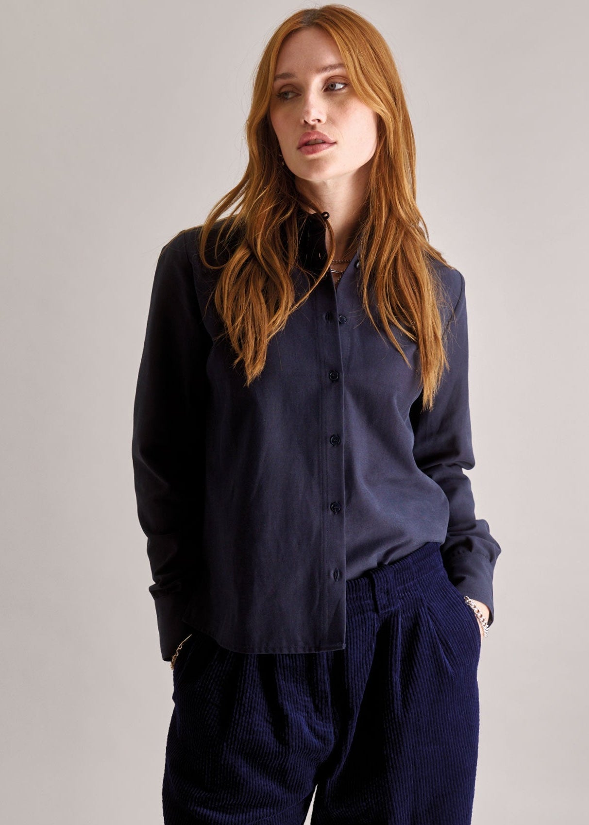 Woman wearing a navy blue shirt and pants against a plain background