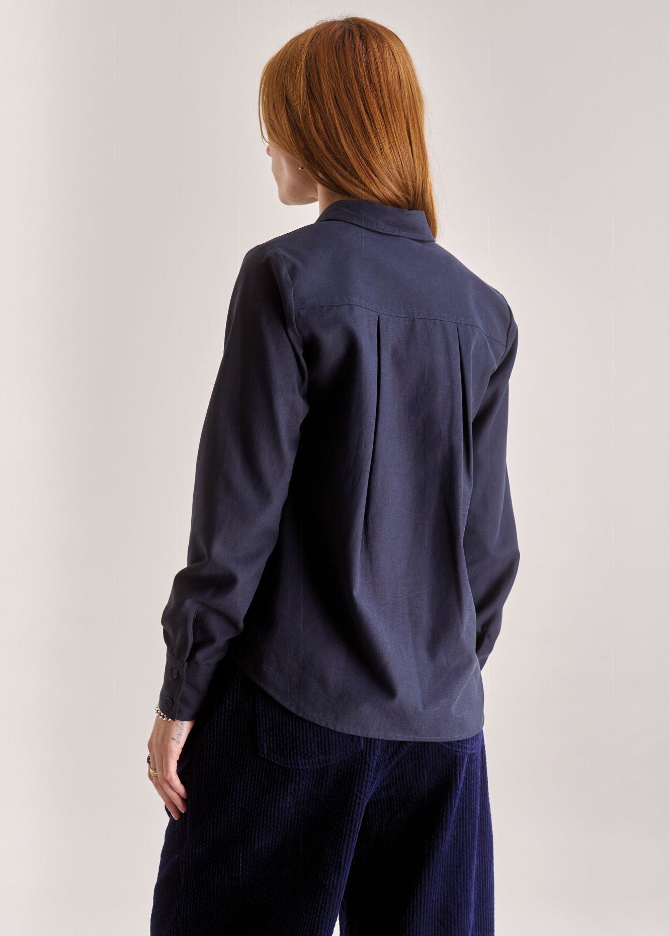 Person wearing a navy blue shirt and pants on a plain background