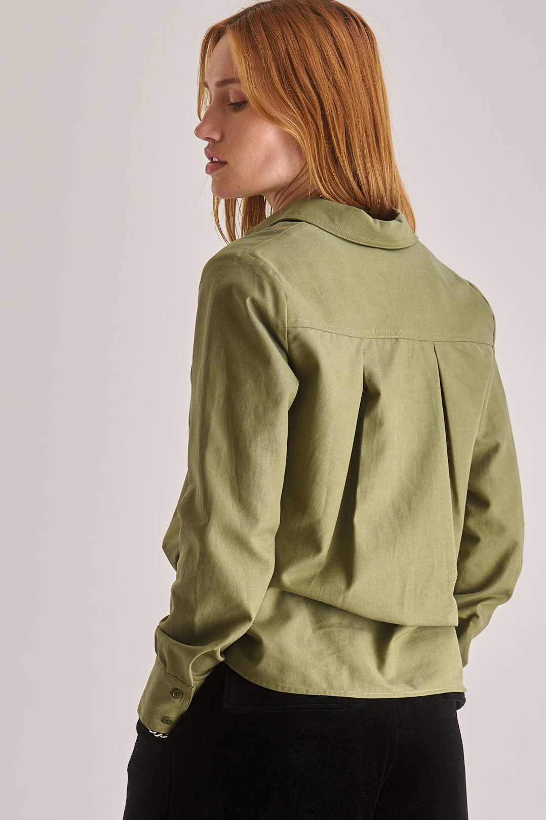 Person wearing a green jacket on a plain background
