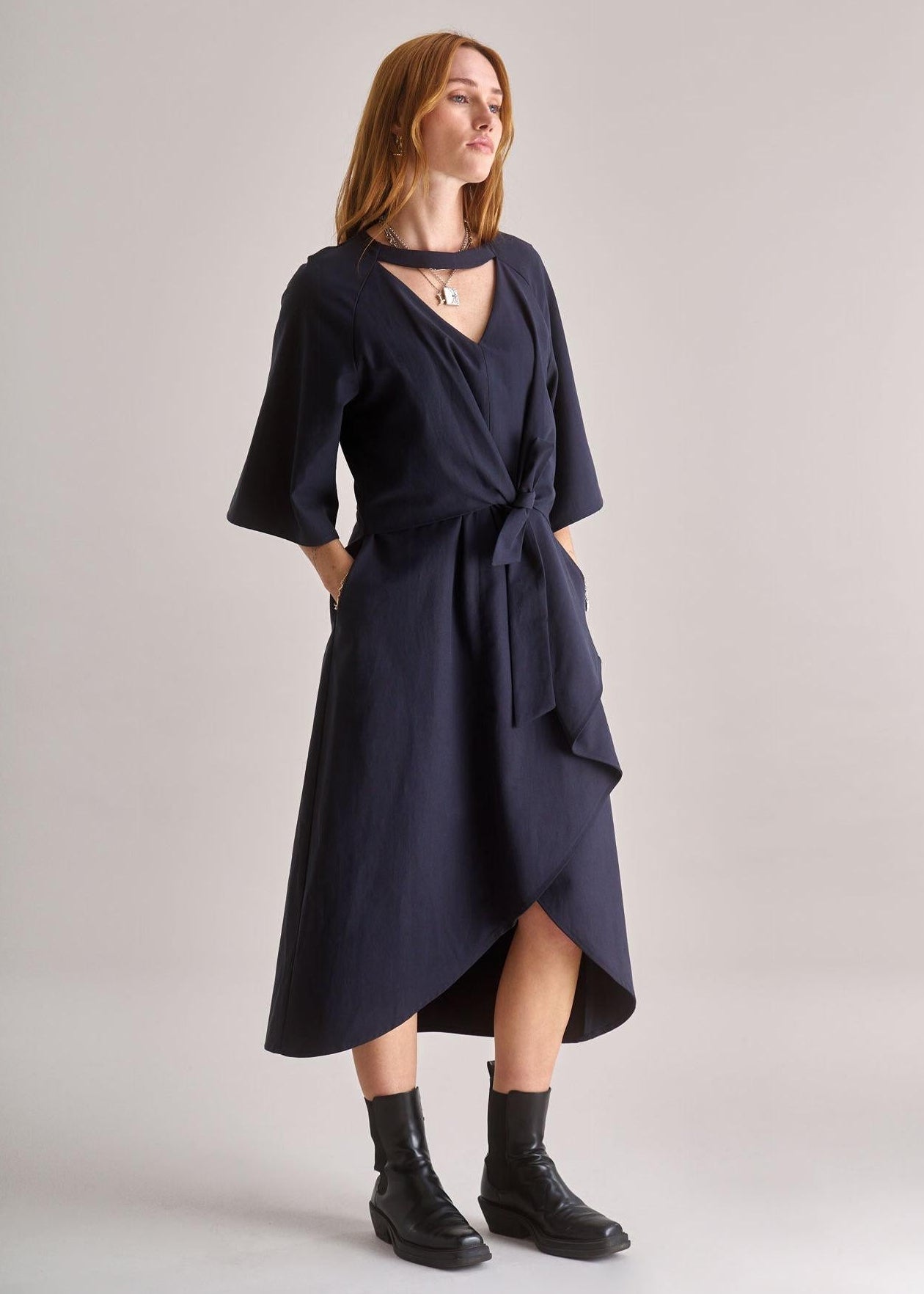 Woman wearing a navy blue dress with a belt on a light gray background