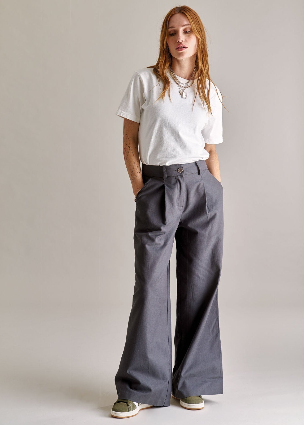 Person wearing a white t-shirt and gray wide-leg pants against a plain background