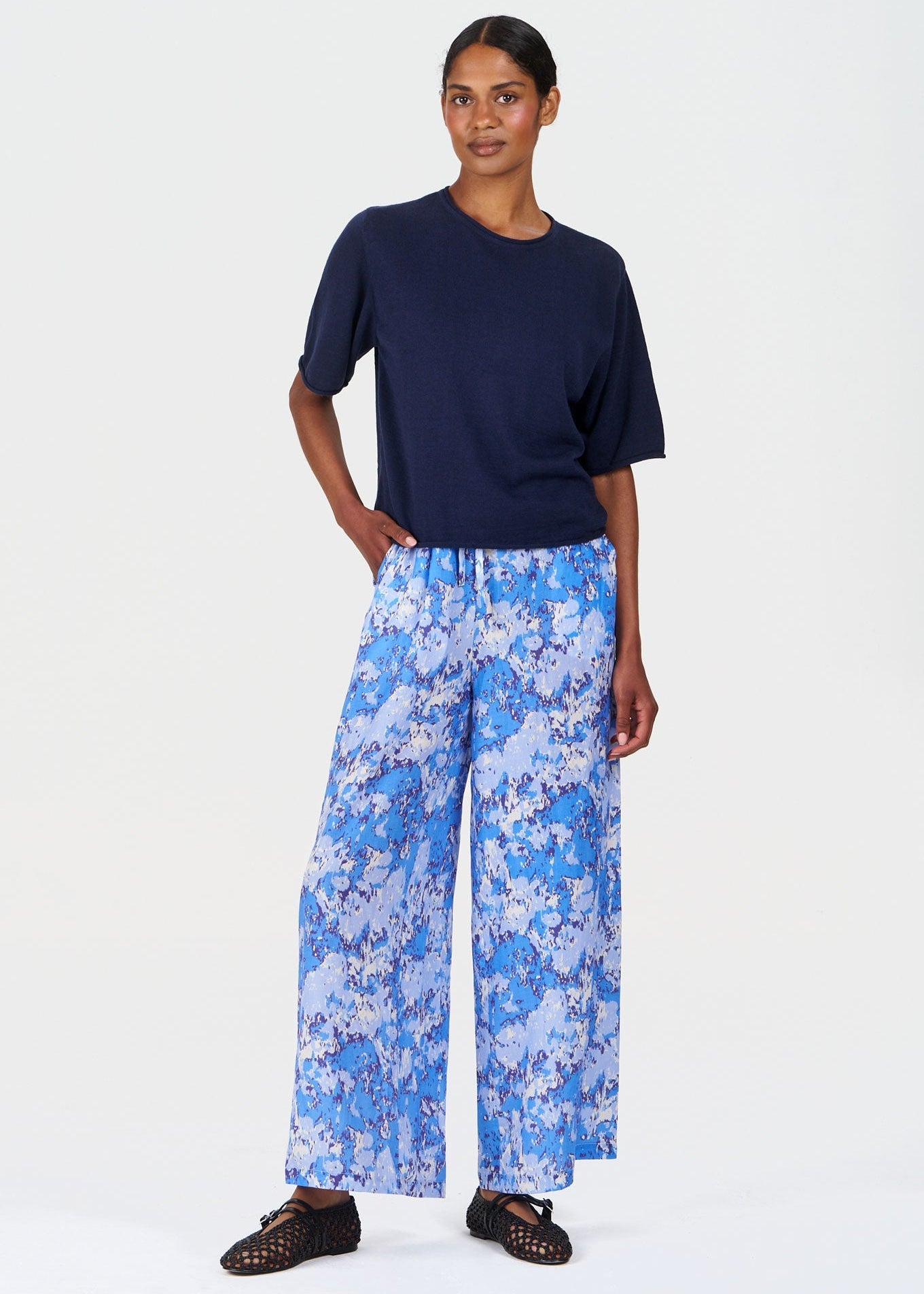Woman wearing a navy top and blue floral pants on a white background