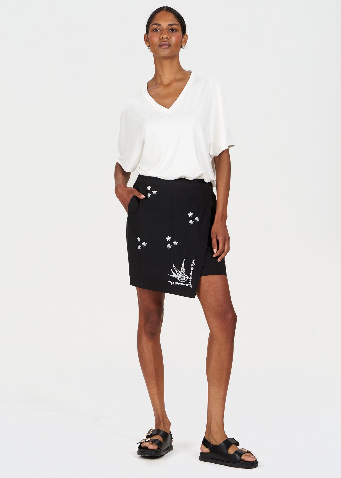 Model wearing WILLOW Organic Cotton Skirt - Black with floral details, paired with a white top and sandals.
