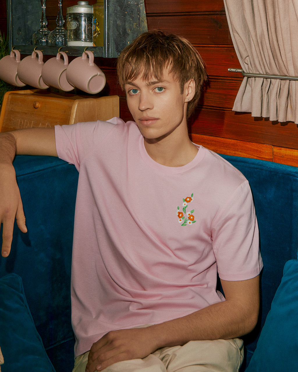 a boy sitting down in a pink tee