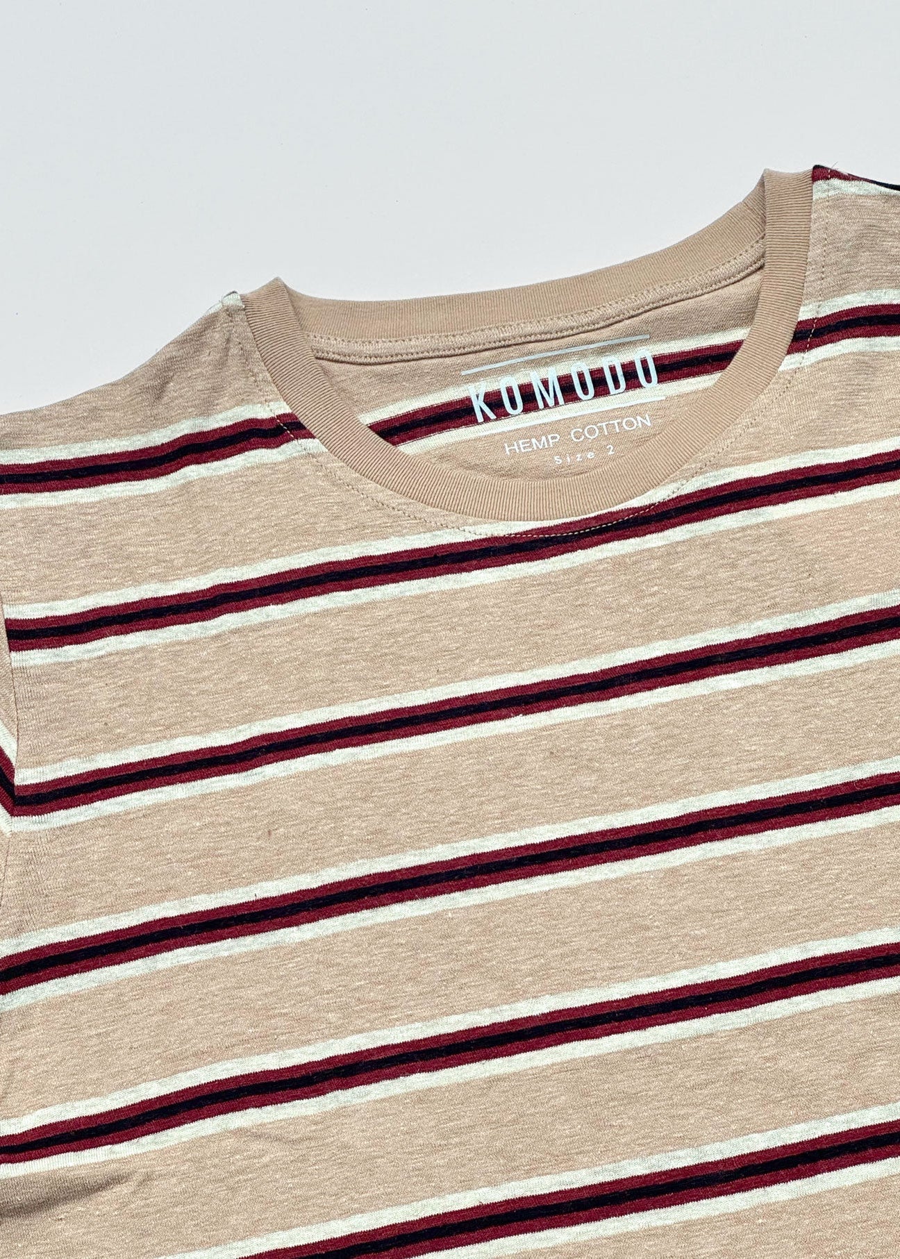 Beige t-shirt with red and white stripes on a light gray background