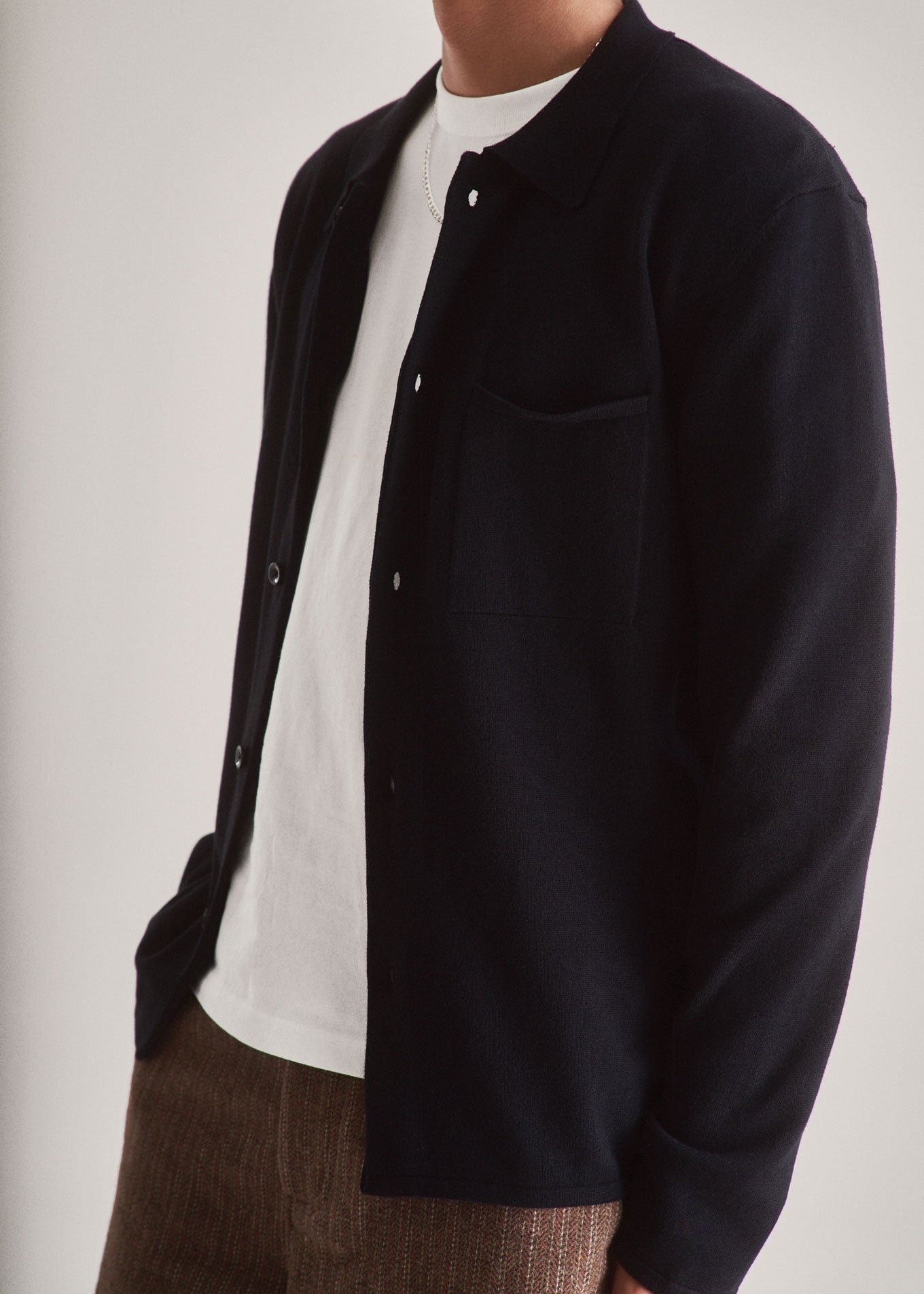 Person wearing a black shirt over a white shirt with a neutral background
