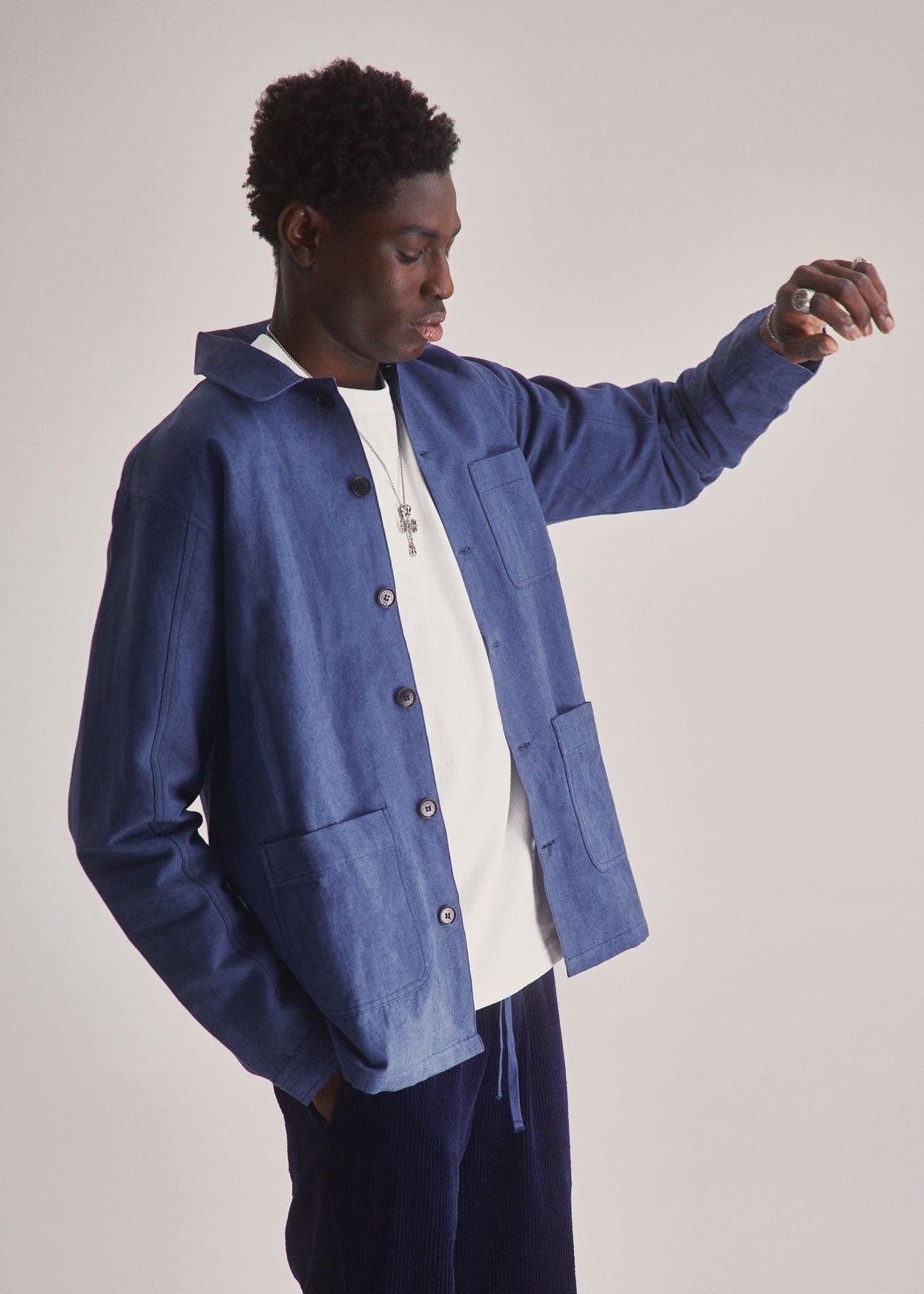 Person wearing a blue jacket over a white shirt with dark pants on a plain background