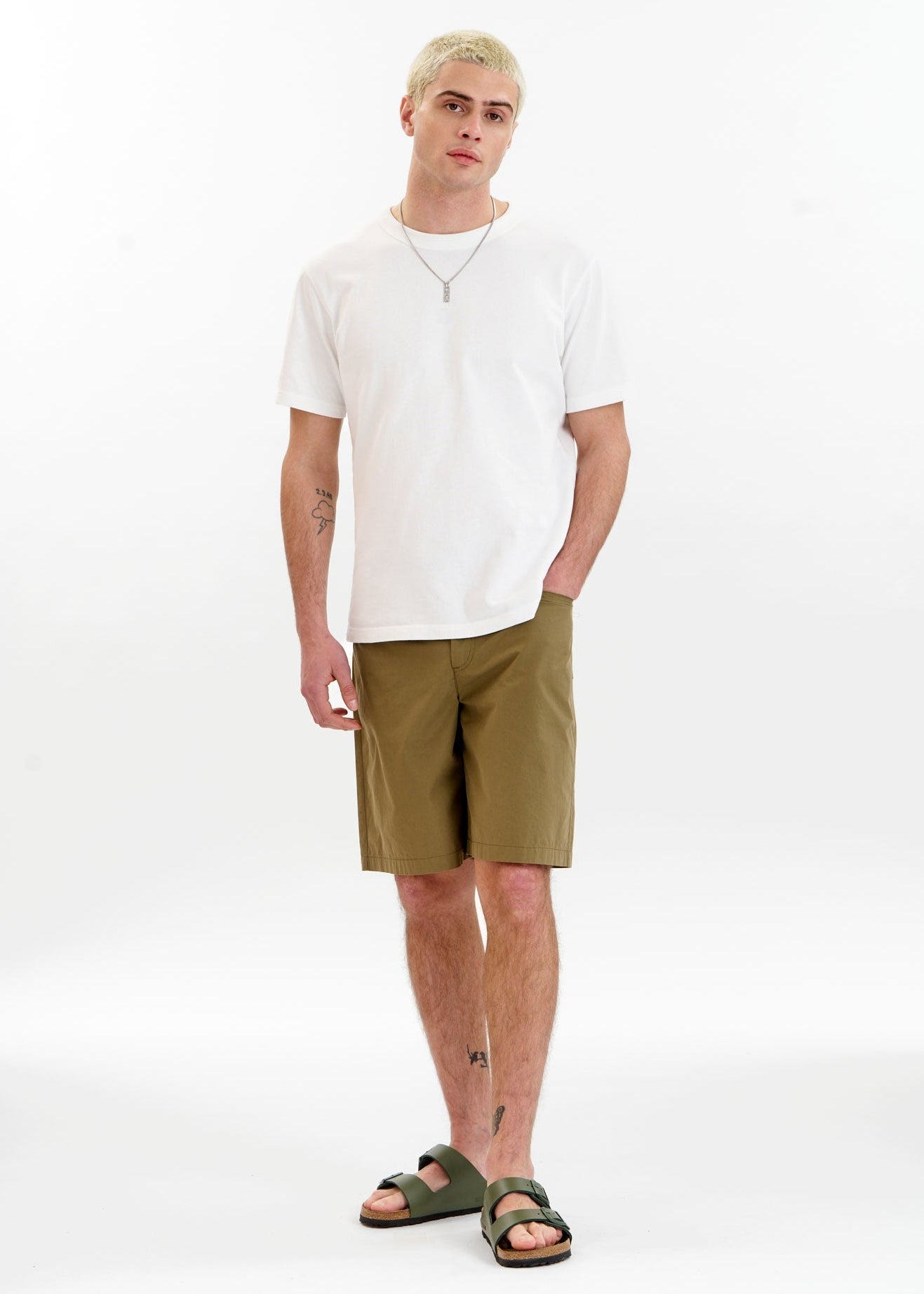 Man wearing a white shirt and green shorts on a white background