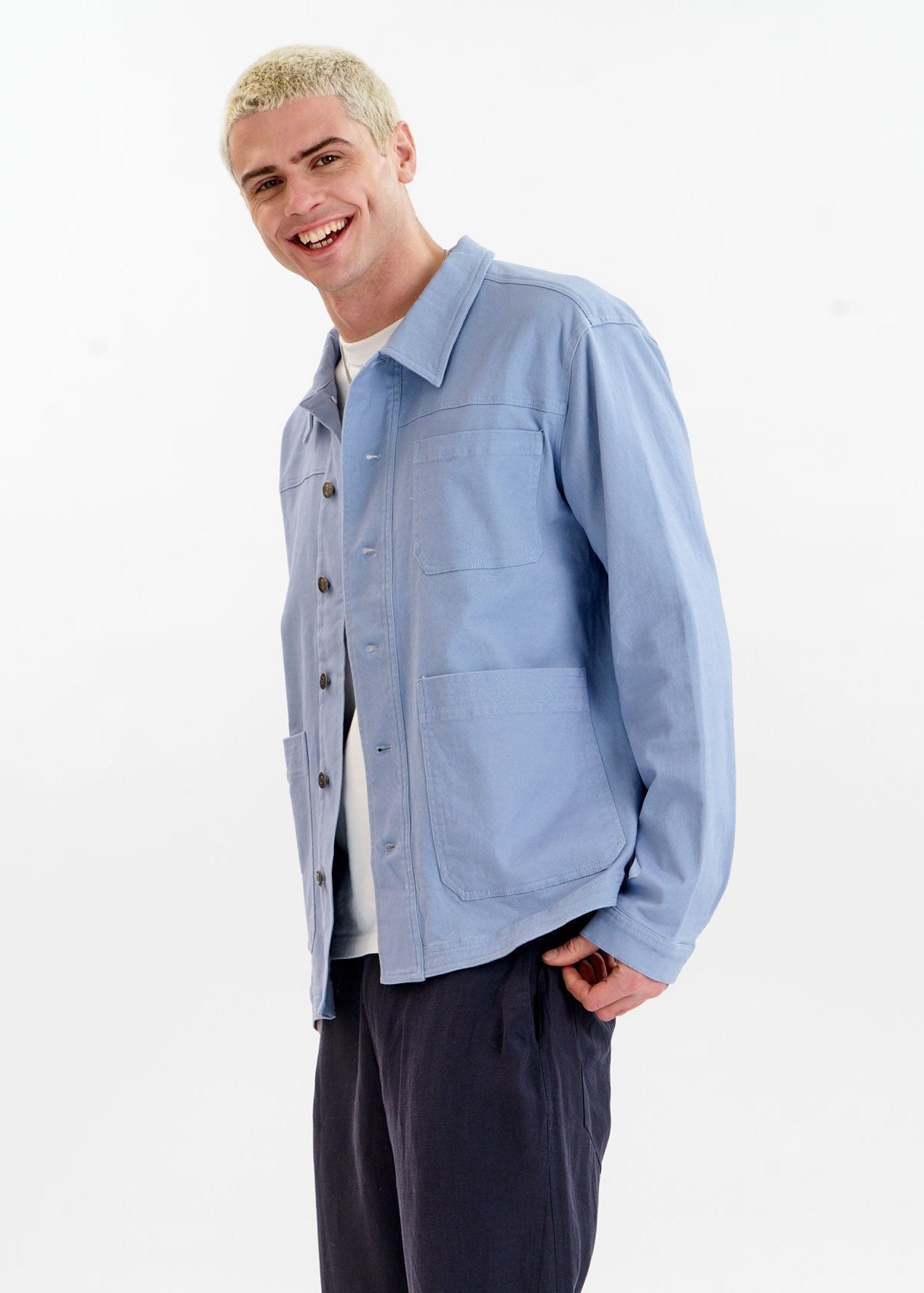 Man wearing a light blue jacket over a white shirt on a white background