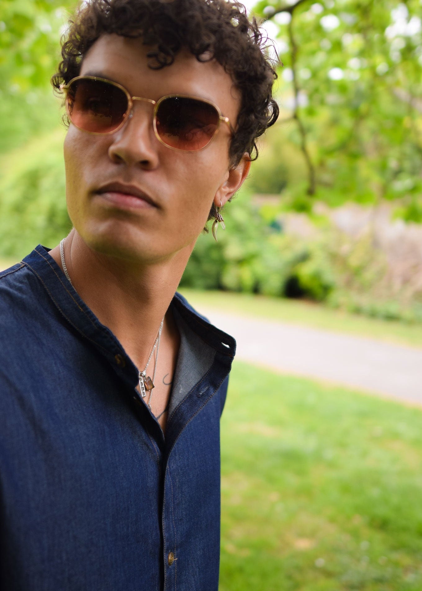 Man wearing sunglasses and a blue shirt in a park setting