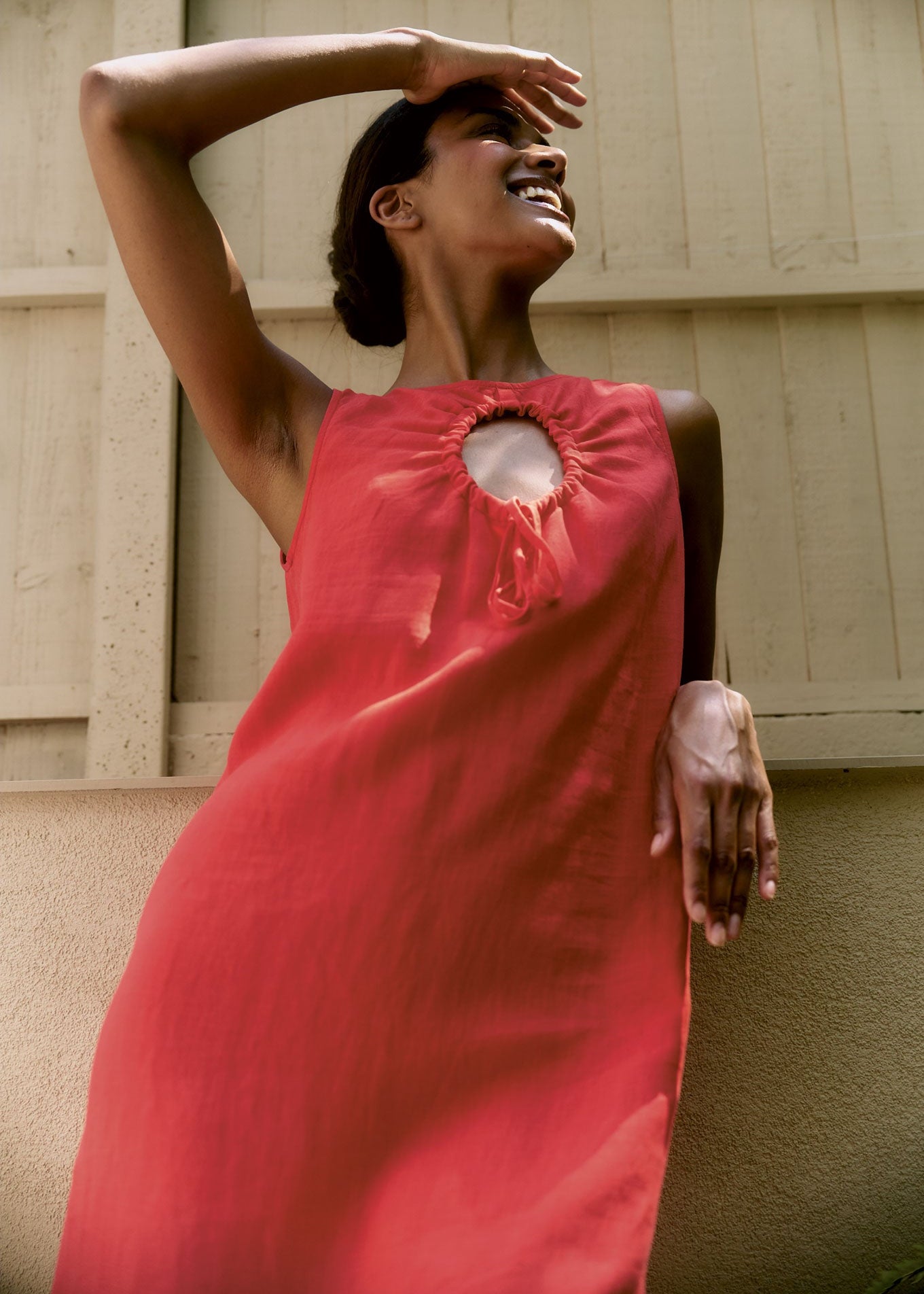 Woman in a red dress standing against a beige wall