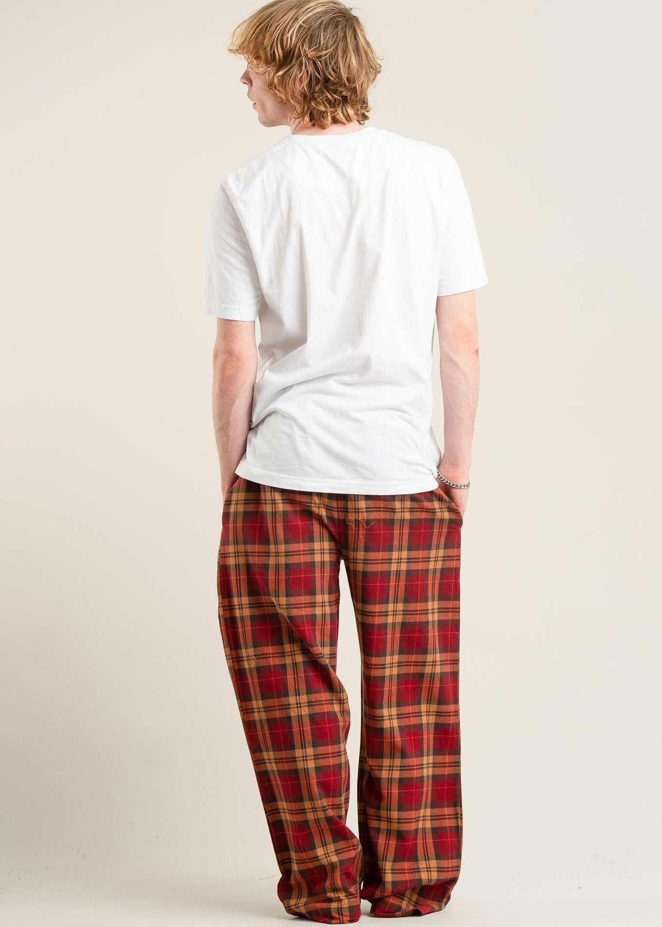 Person wearing a white t-shirt and red plaid pants on a beige background