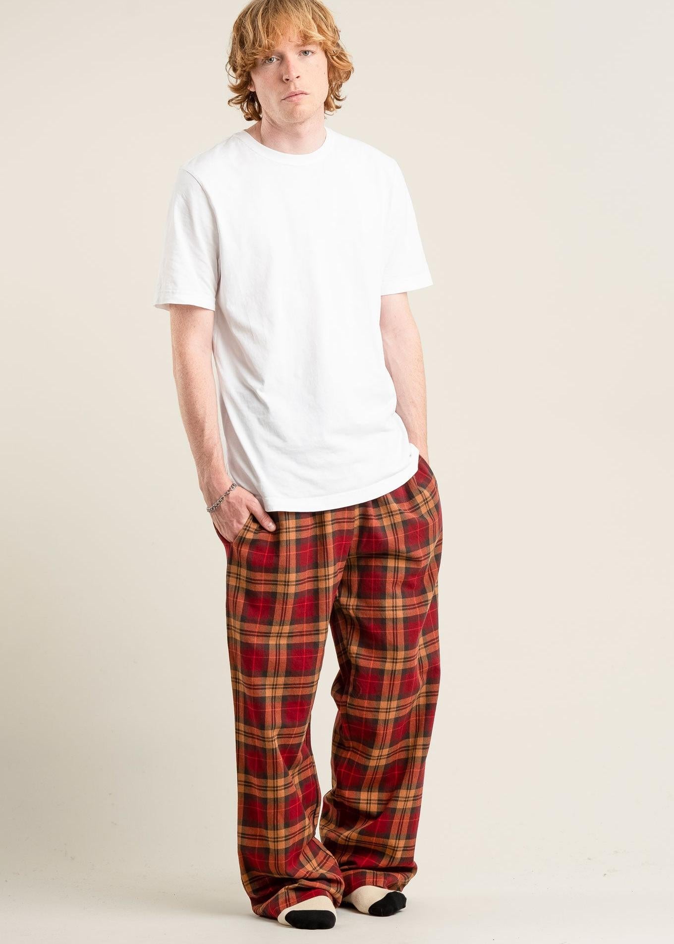 Person wearing a white t-shirt and red plaid pants on a plain background