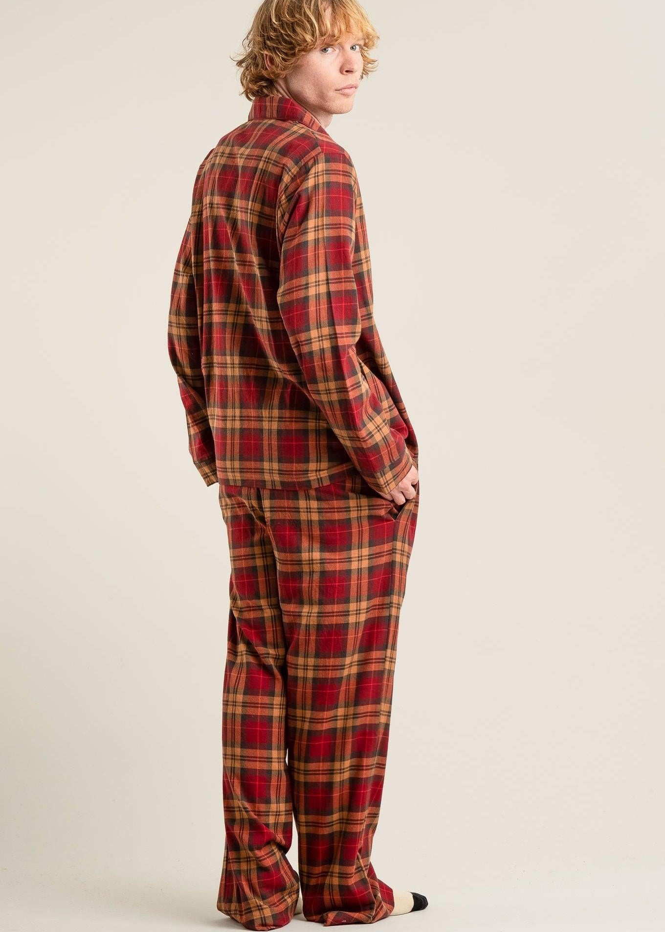Person wearing a red and brown plaid pajama set on a beige background