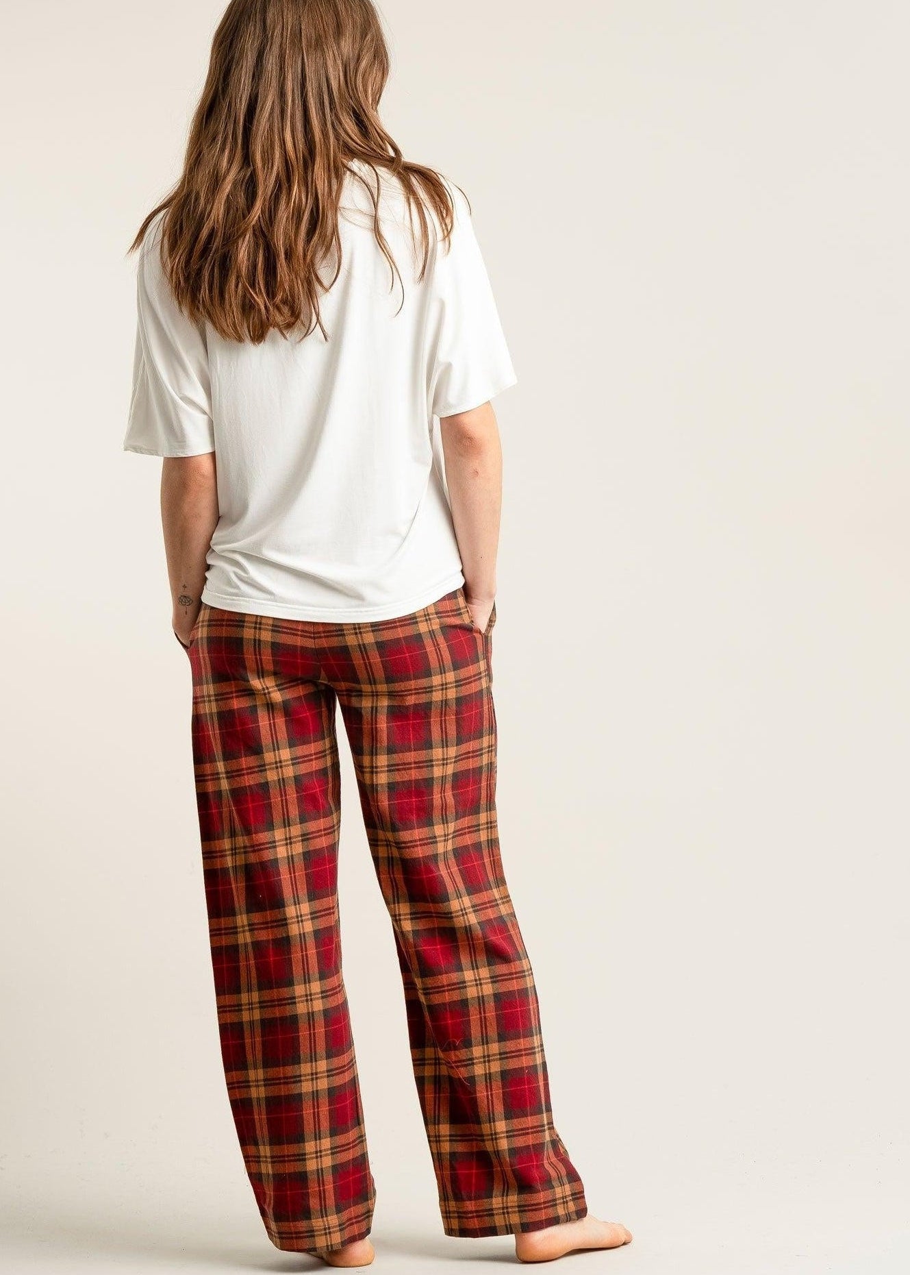 Person wearing red plaid pants and a white shirt on a plain background
