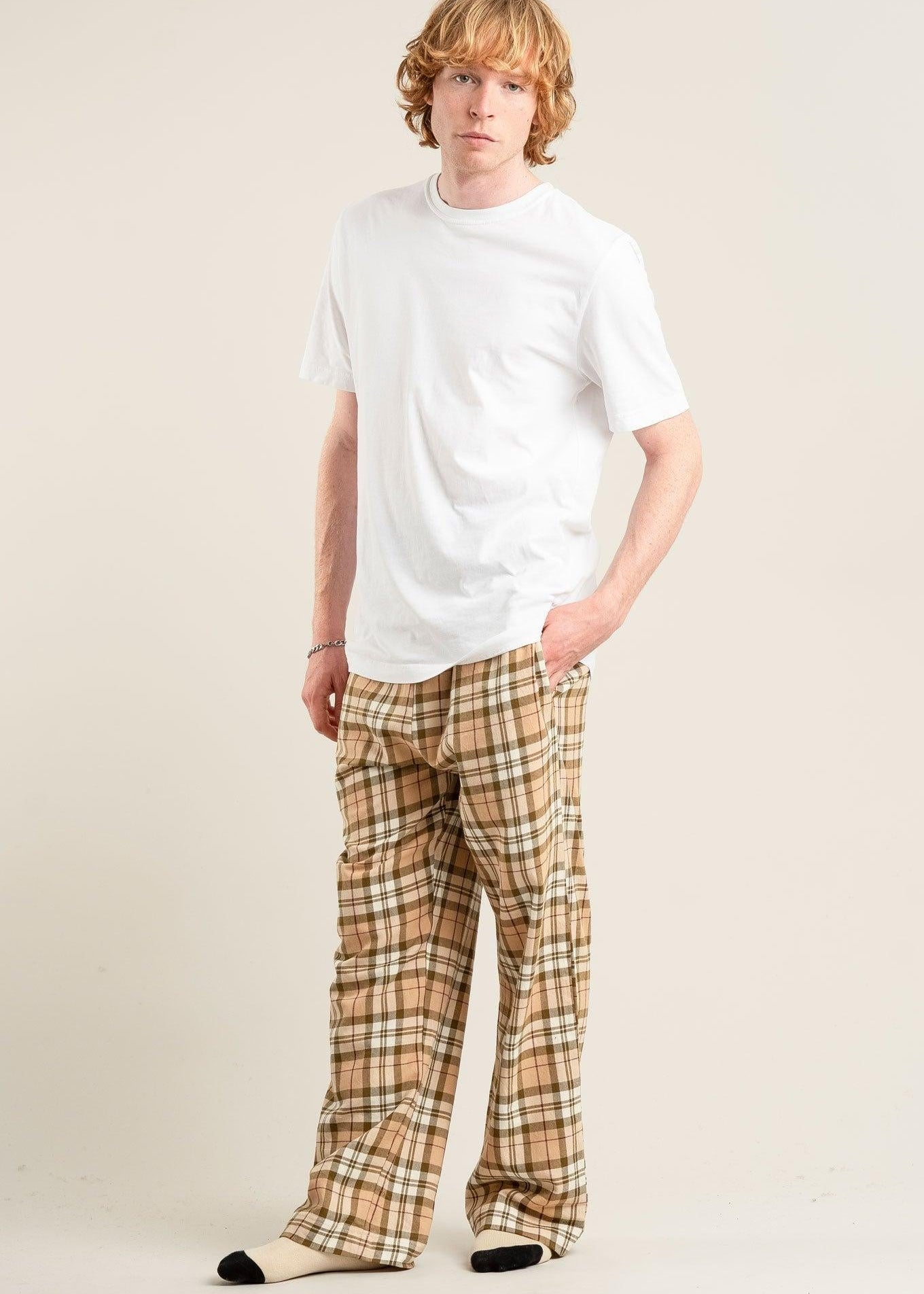 Person wearing a white t-shirt and plaid pants on a plain background