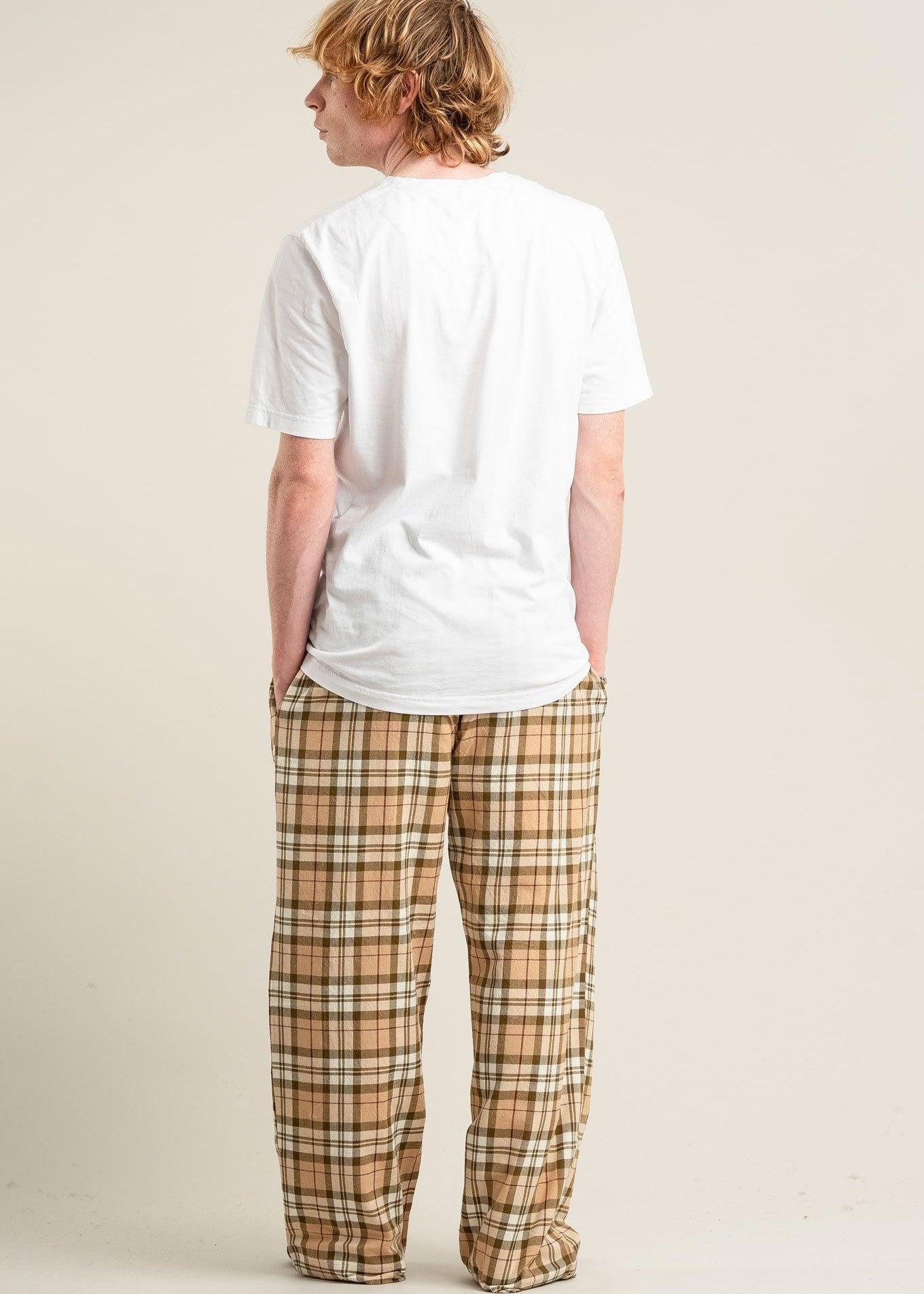 Person wearing a white t-shirt and plaid pants on a beige background