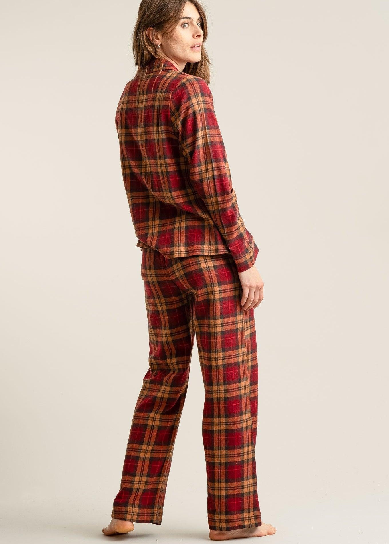 Person wearing red and gold plaid pajamas on a beige background