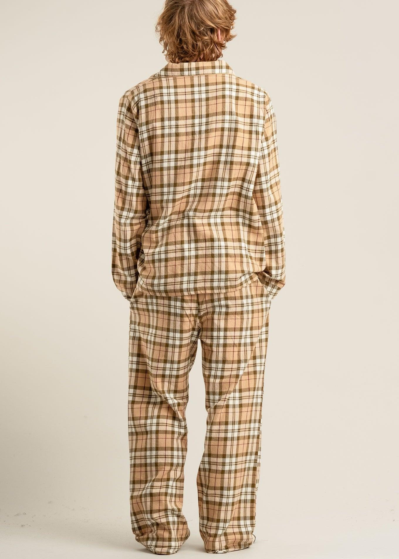 Person wearing a plaid pajama set on a plain background