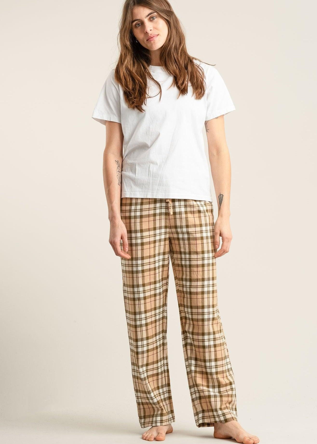 Woman wearing a white t-shirt and plaid pants on a plain background