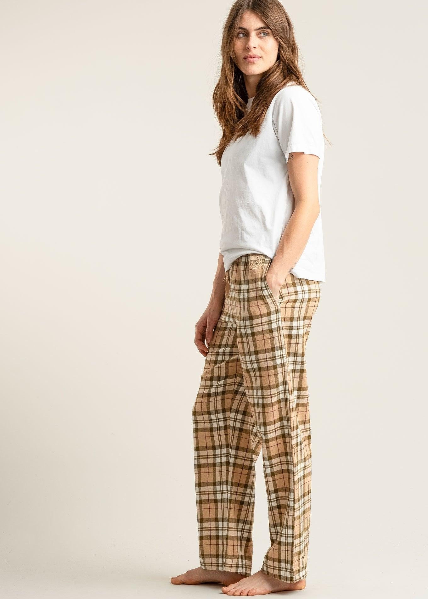 Woman wearing a white t-shirt and plaid pants on a plain background