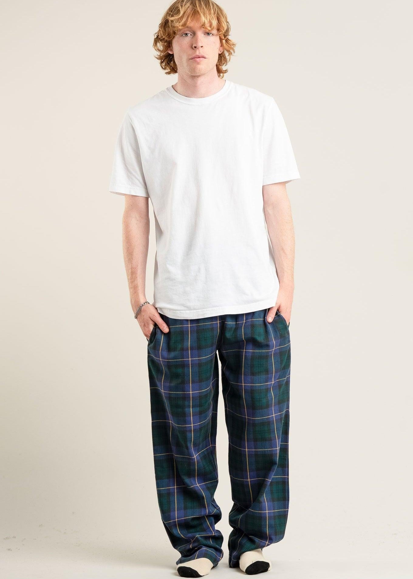 Person wearing a white t-shirt and plaid pants on a plain background